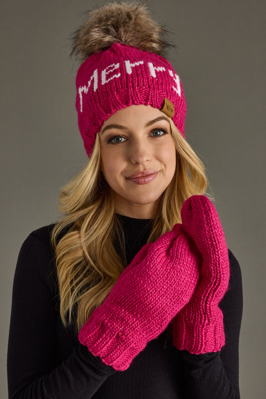 Woman wearing a pink knit hat and mittens with 'Merry' text on a gray background