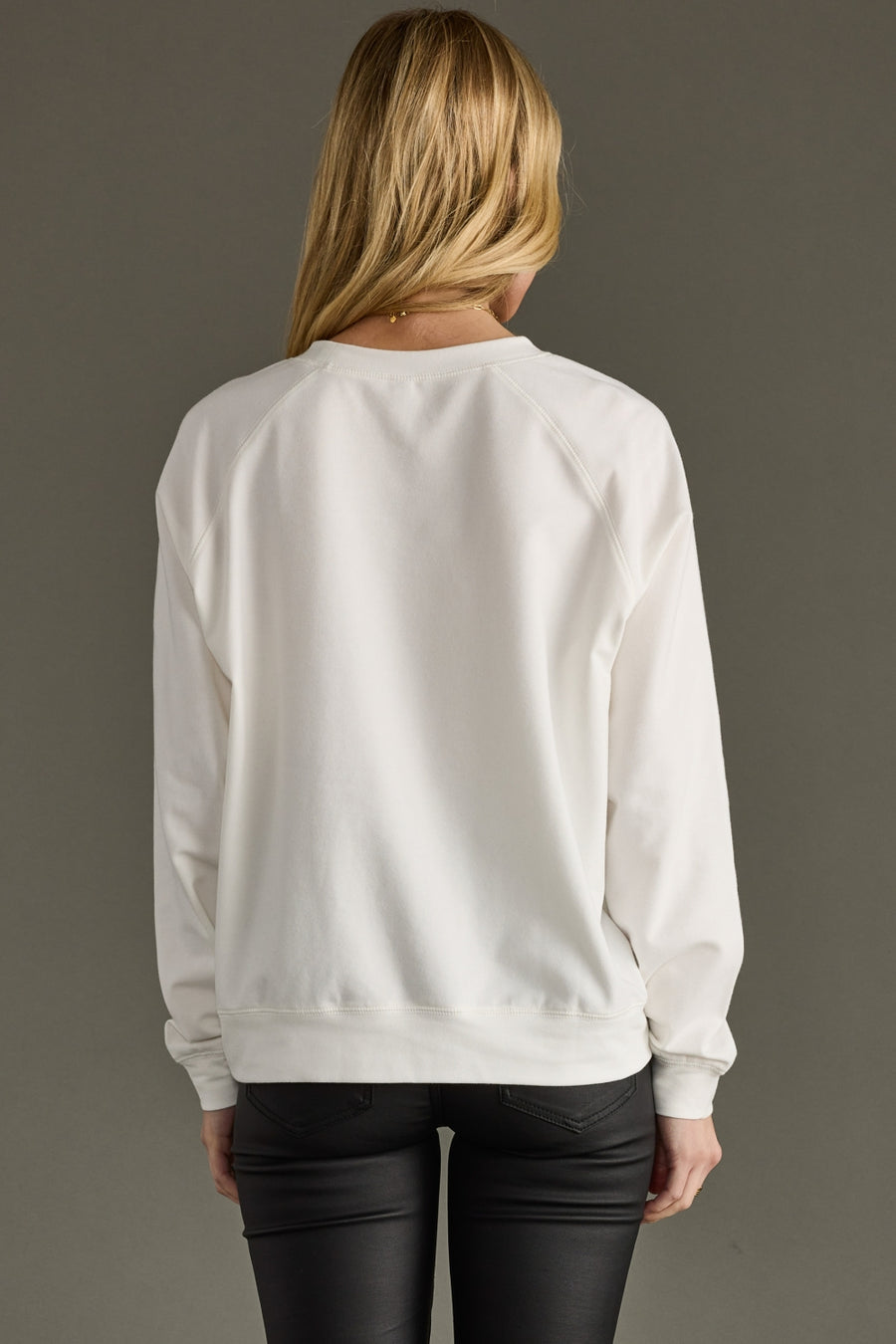 Person wearing a white sweatshirt with a plain background