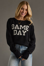 Woman wearing a black 'GAME DAY' sweater against a gray background