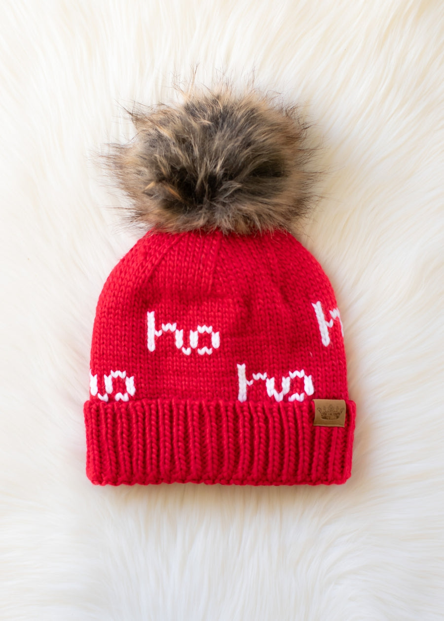 Red knit beanie with fur pom-pom and 'ho ho ho' text on a white background