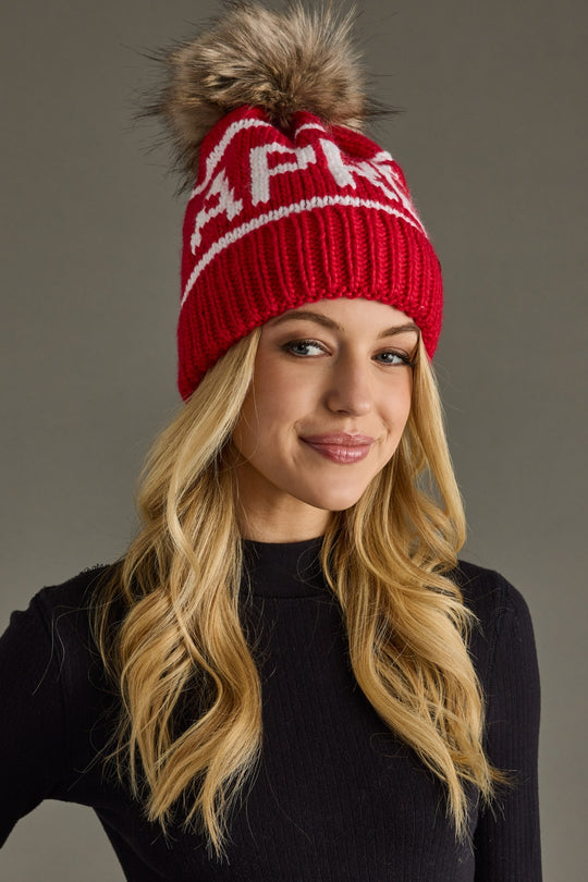 Woman wearing a red knit hat with a pom-pom on a gray background