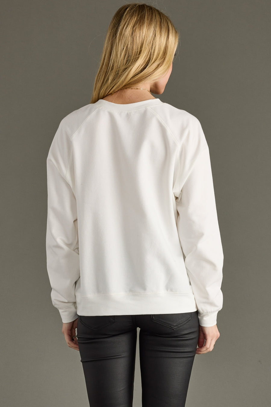 Person wearing a white sweatshirt with a plain background