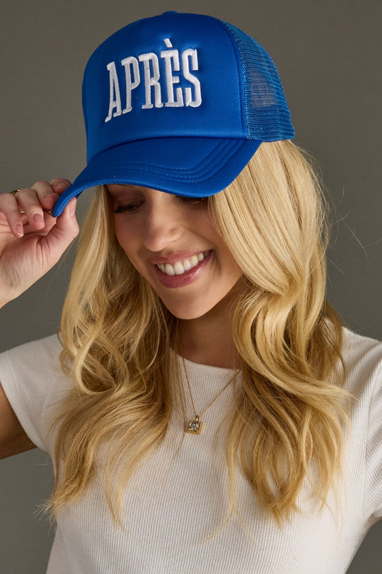 Woman wearing a blue cap with 'APRèS' text against a gray background