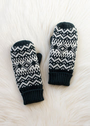 Pair of dark teal and white patterned mittens on a white textured surface