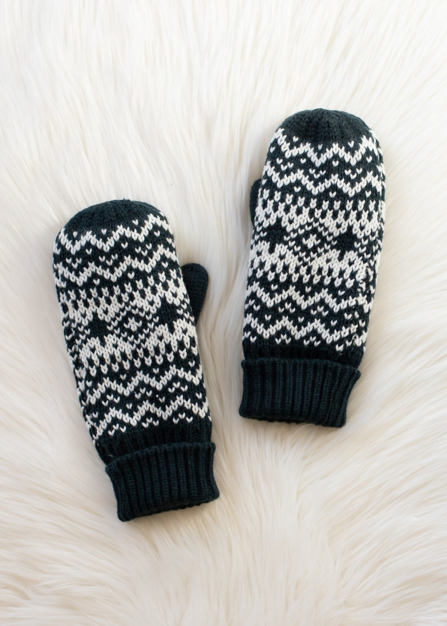 Pair of dark teal and white patterned mittens on a white textured surface
