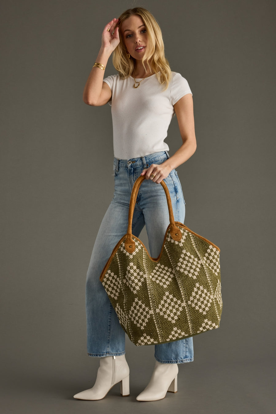 Woman holding Panache Apparel Collection’s olive and cream woven diamond tote bag with tan handles.