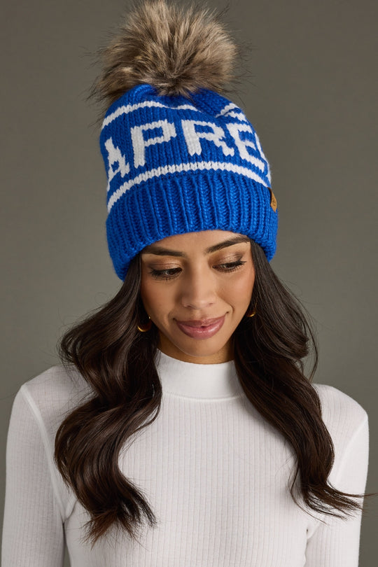 Woman wearing a blue beanie with a pom-pom on a gray background