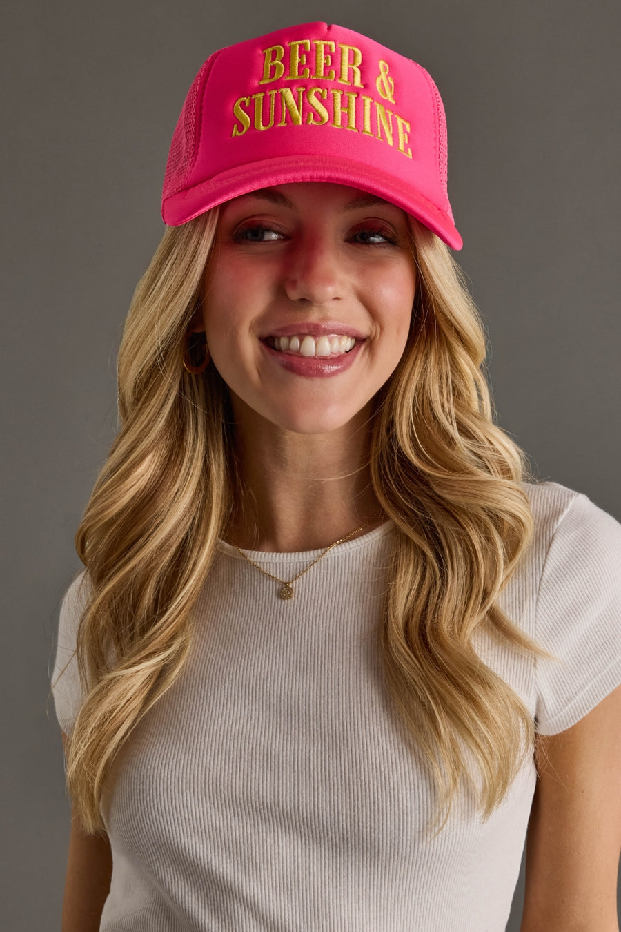 Woman wearing a pink cap with 'BEER & SUNSHINE' text on a gray background