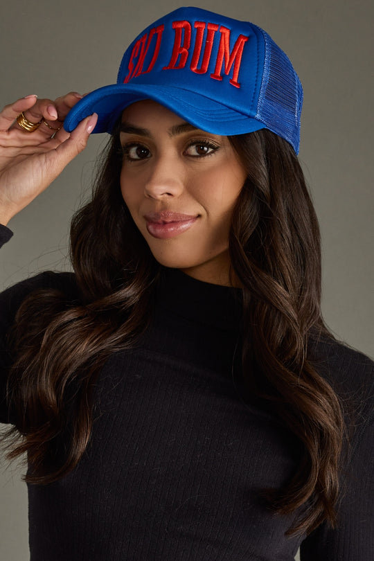 Woman wearing a blue cap with red text against a neutral background
