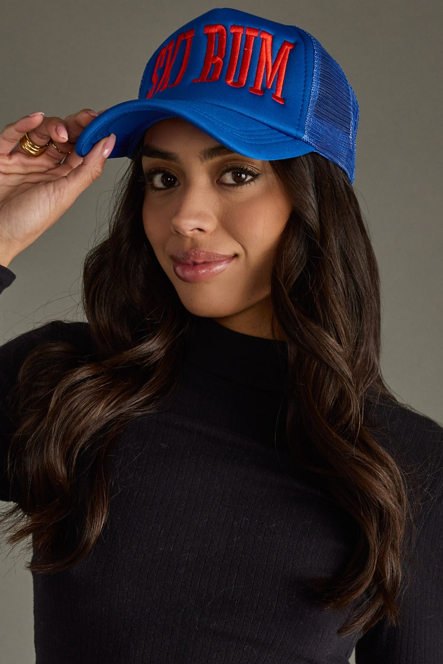Woman wearing a blue cap with red text against a neutral background