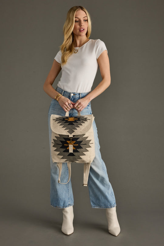 Woman holding a patterned bag against a gray background