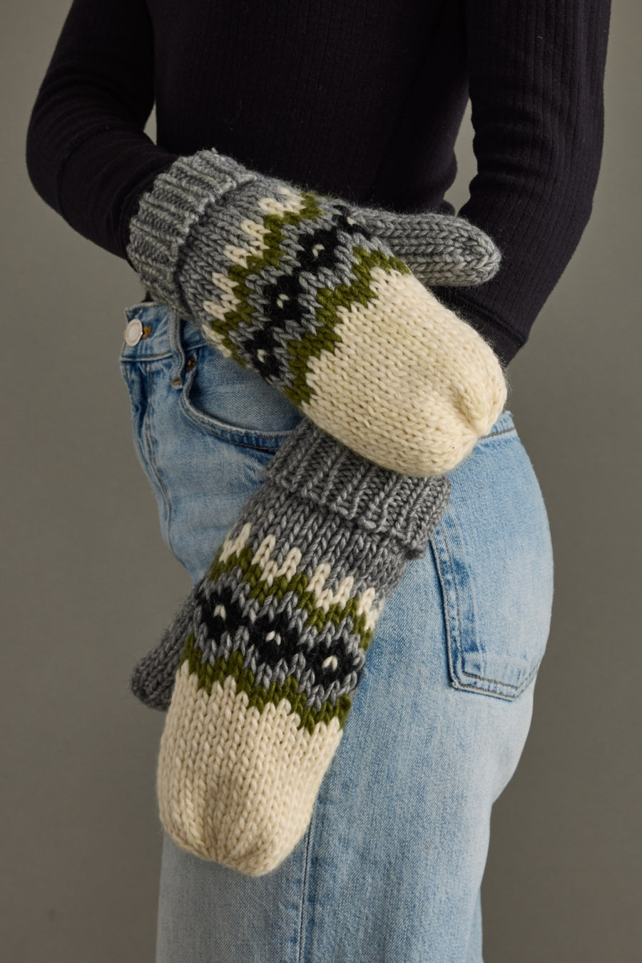 Person wearing patterned mittens with a neutral background
