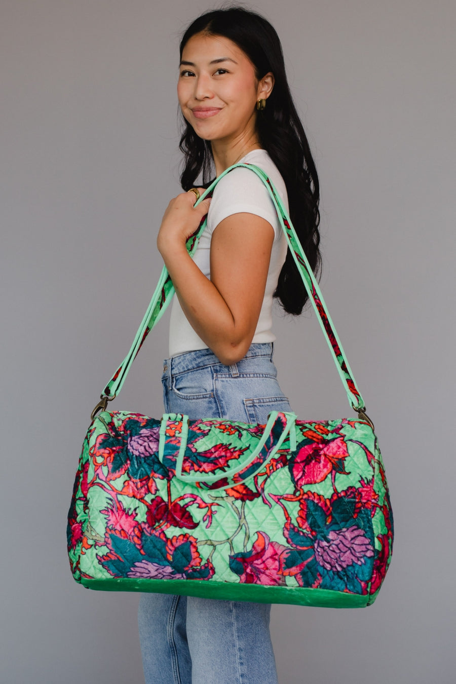 Woman holding a colorful floral-patterned bag against a gray background