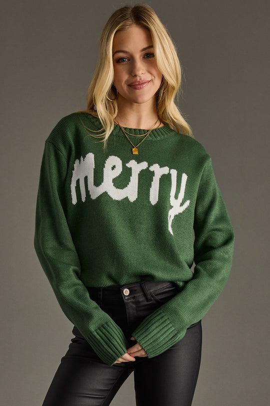 Woman wearing a green sweater with 'merry' text on a gray background