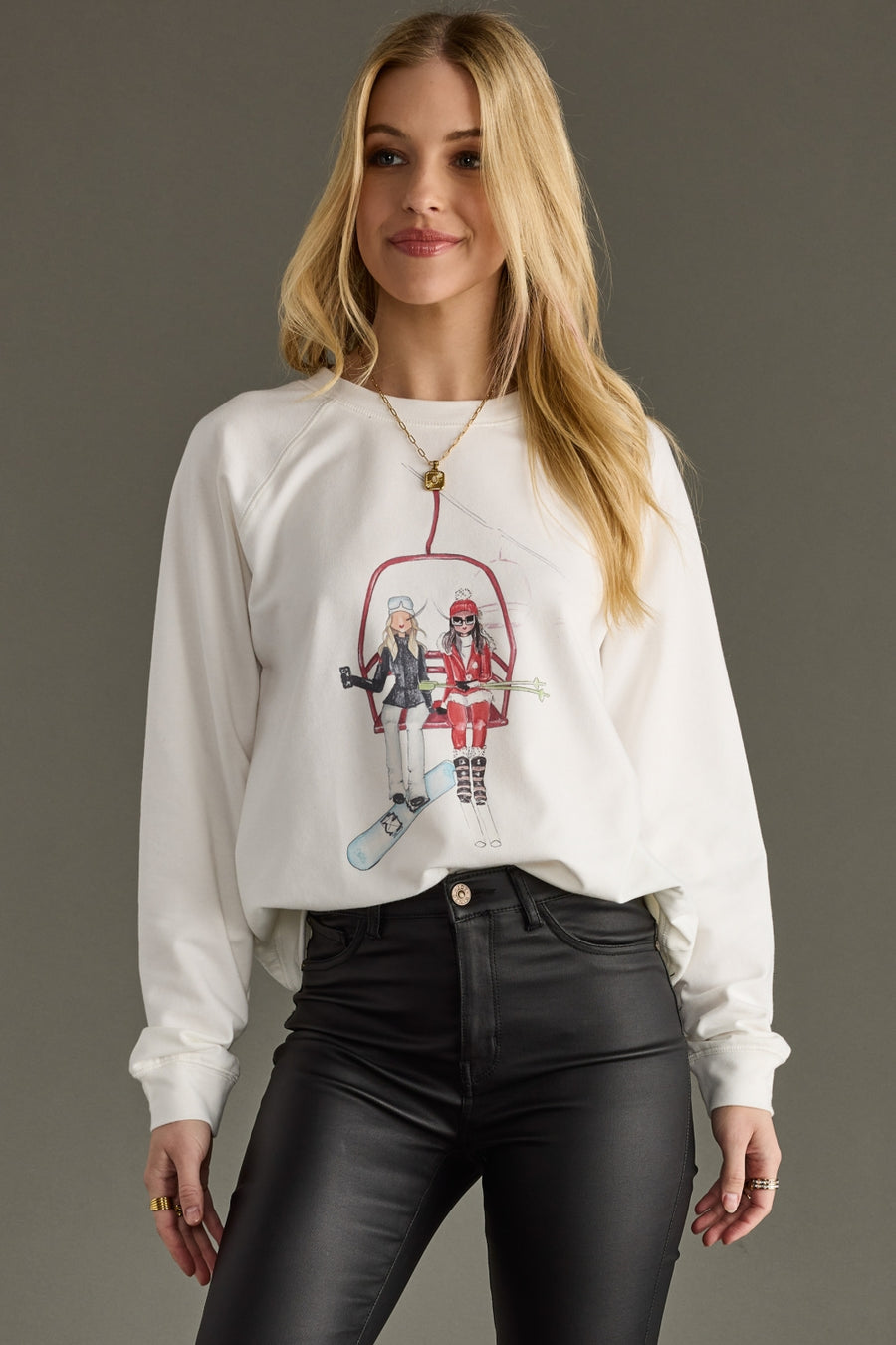 Woman wearing a white sweatshirt with graphic design on a gray background