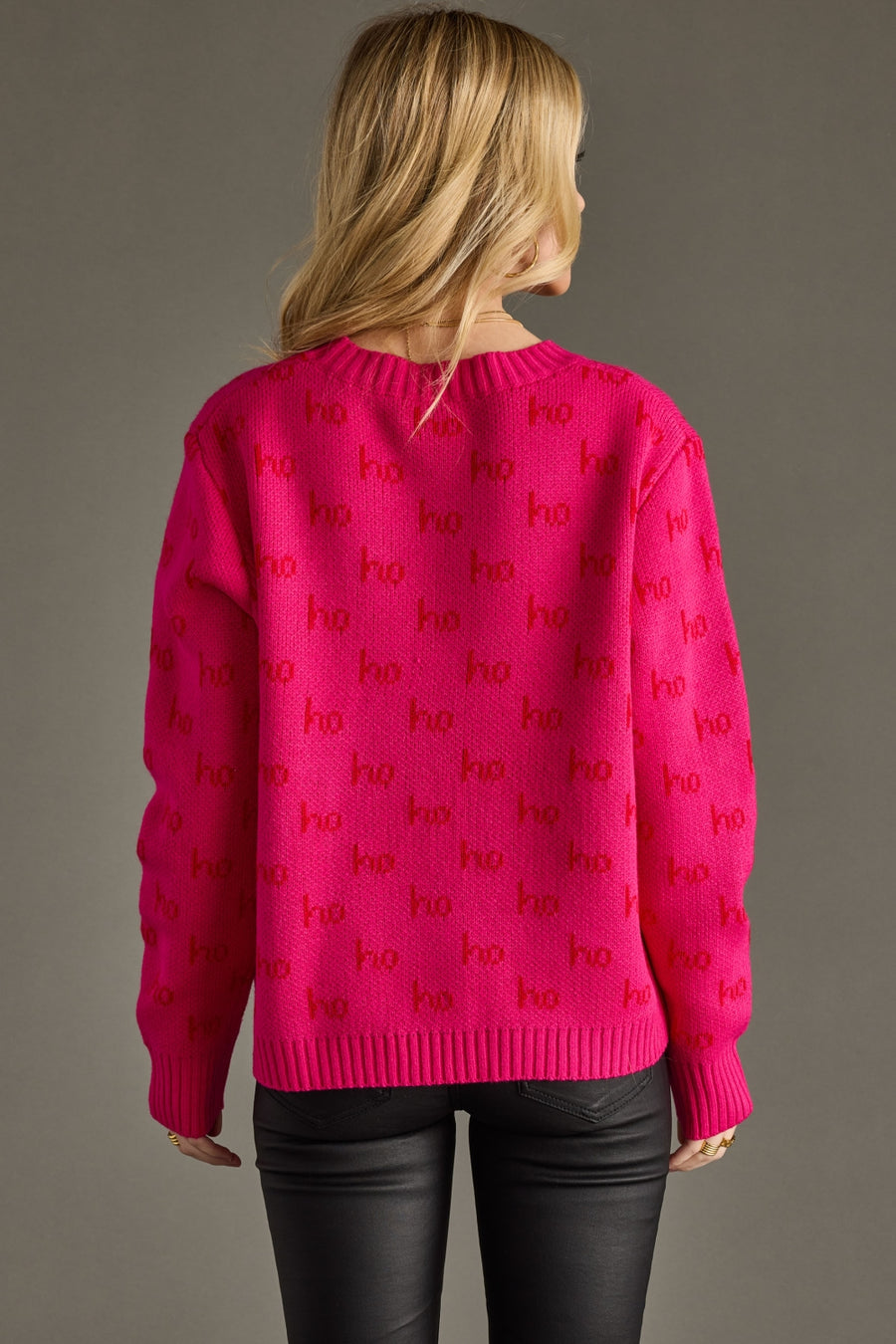 Person wearing a bright pink sweater with 'ho ho ho' pattern on a gray background