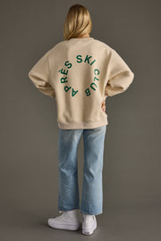 Person wearing a beige sweatshirt with green text on the back against a gray background