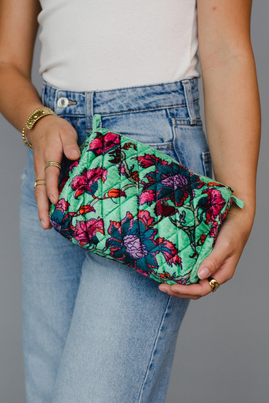 Person holding a floral quilted travel pouch against a gray background