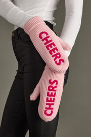 Pink mittens with 'CHEERS' text worn by a person against a neutral background