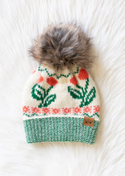 Knitted hat with floral pattern and fur pom-pom on a white background