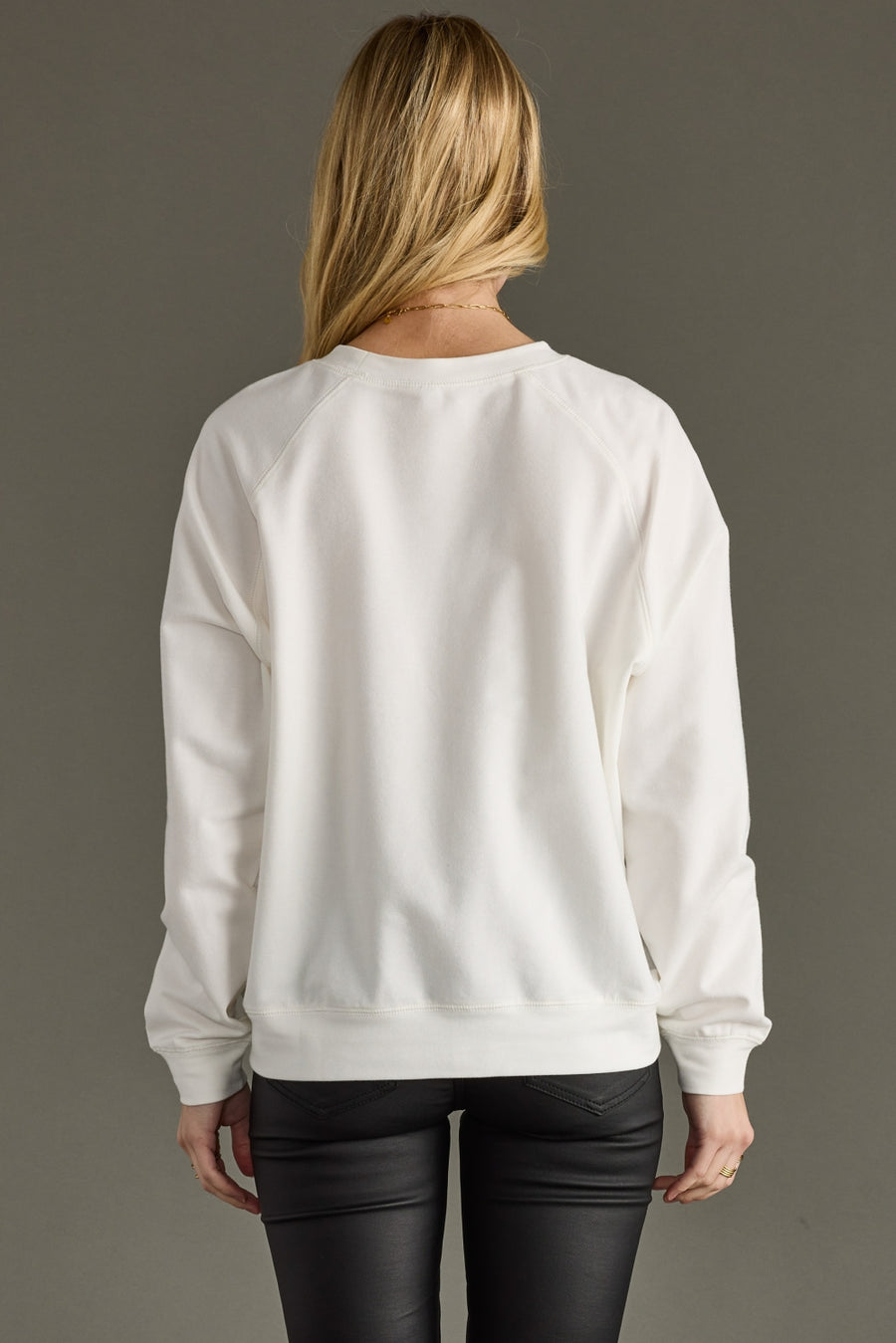 Person wearing a white sweatshirt with a plain background