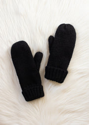 Pair of black mittens on a white fur surface