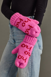 Person wearing pink mittens with text, standing against a neutral background