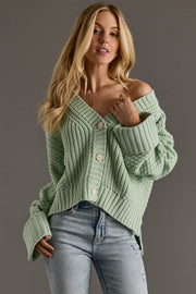 Woman wearing a green knitted cardigan against a gray background