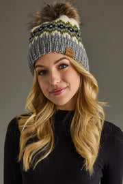 Woman wearing a patterned knit beanie with a pom-pom on a gray background
