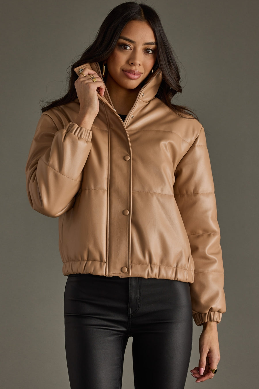 Woman wearing a beige jacket against a gray background