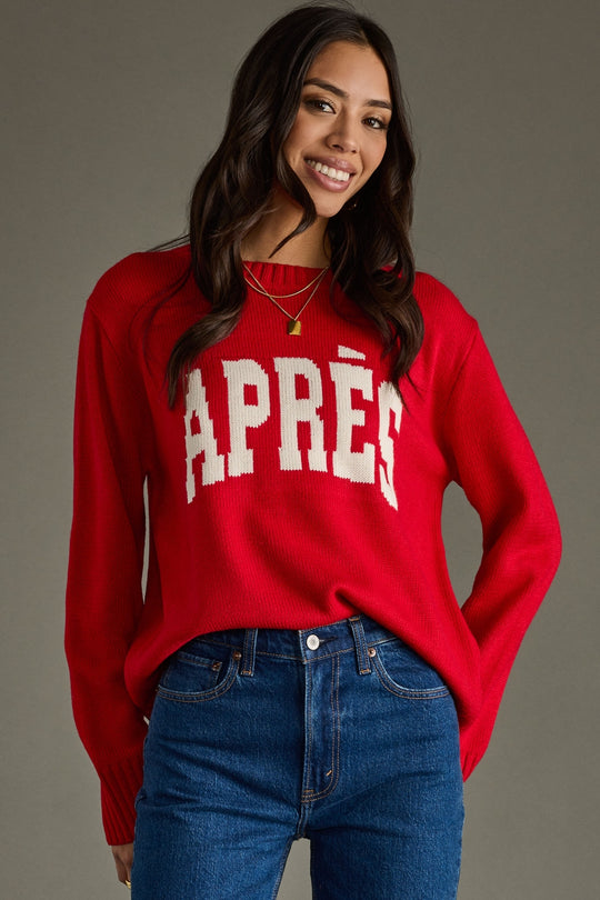 Woman wearing a red sweater with 'APRèS' text, standing against a gray background