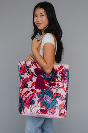 Woman holding a pink floral tote bag against a gray background