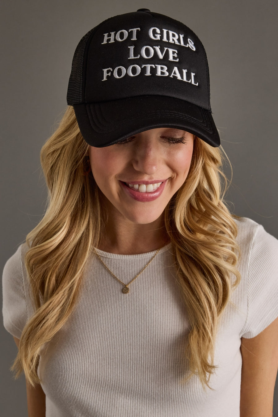Woman wearing a black cap with 'HOT GIRLS LOVE FOOTBALL' text on a gray background