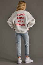 Person wearing a white sweatshirt with red text on the back, standing against a gray background