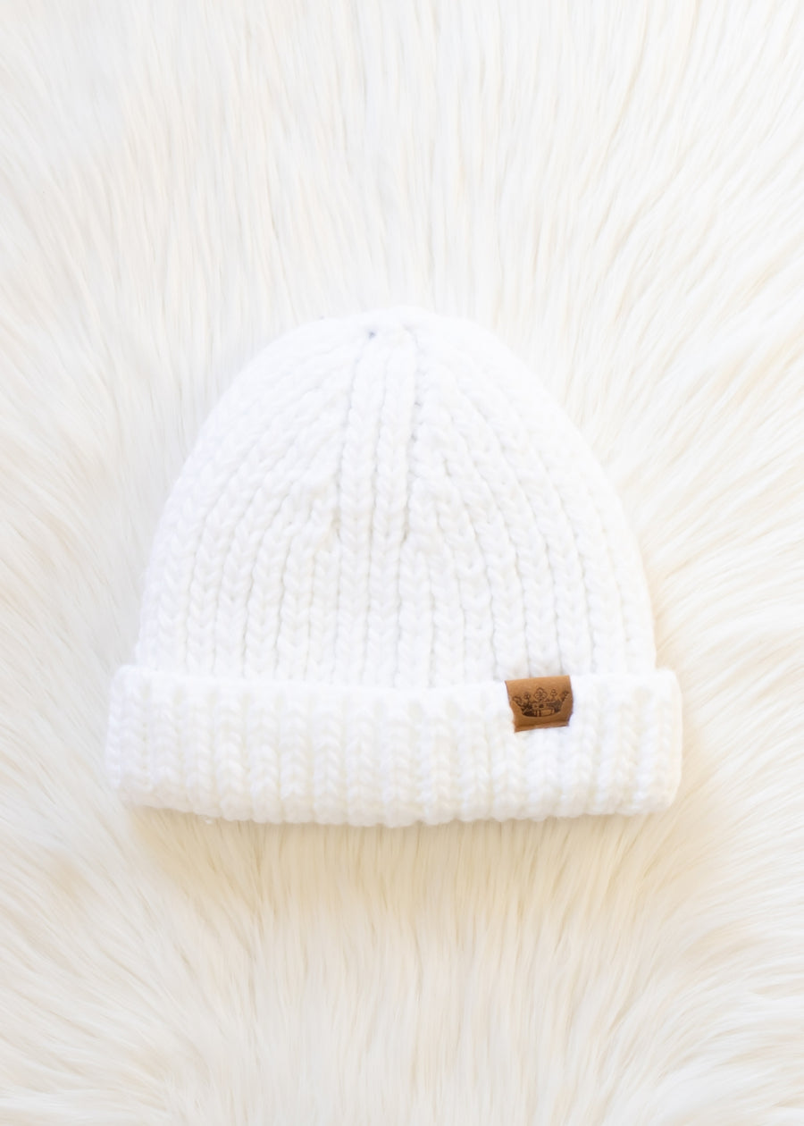 White knit beanie with a brown tag on a white background