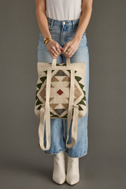 Person holding a patterned tote bag against a plain background