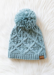 Blue knitted beanie with a pom-pom on a white background