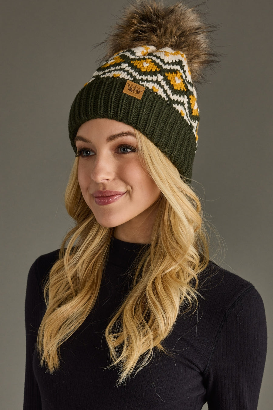 Woman wearing a patterned beanie with a pom-pom on a gray background
