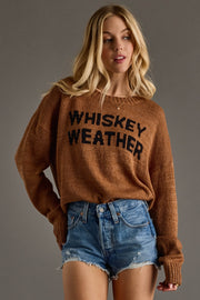 A cozy camel-brown knit sweater featuring bold black “Whiskey Weather” lettering across the front for a playful, seasonal statement. Designed with a relaxed fit, soft textured knit, and a classic crew neckline, this sweater offers all-day comfort with an effortlessly casual feel. Finished with long sleeves and ribbed cuffs and hem, it’s perfect for layering through cool fall days and pairing with your favorite denim.