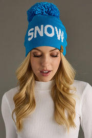 Woman wearing a blue 'SNOW' beanie against a gray background