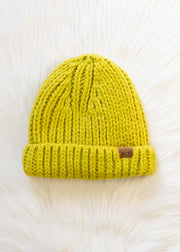 Lime green knit beanie with a brand logo on a white fur background