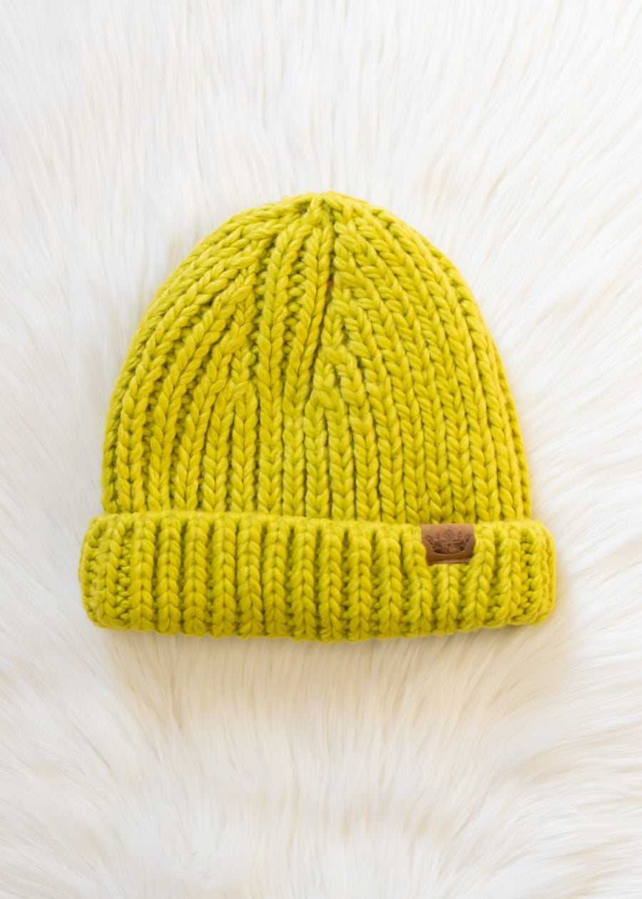 Lime green knit beanie with a brand logo on a white fur background
