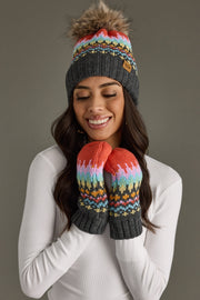 Woman wearing a colorful knit beanie and mittens against a gray background