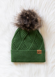 Green knit beanie with fur pom-pom on a white background