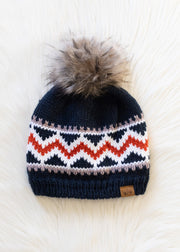 Knitted beanie with a patterned design and fur pom-pom on a white background