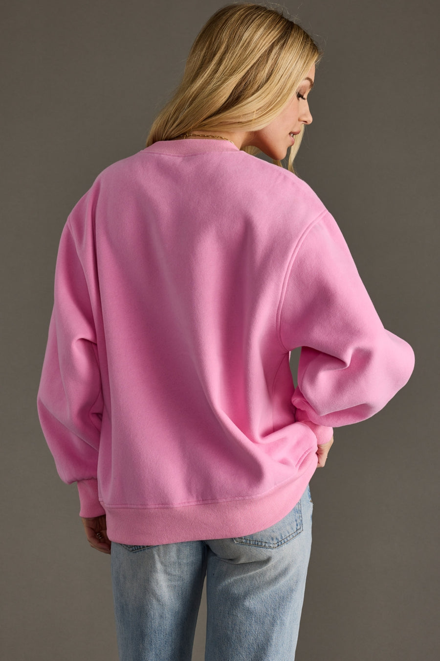Person wearing a pink sweatshirt against a gray background
