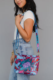 Woman holding a colorful floral-patterned crossbody bag against a gray background