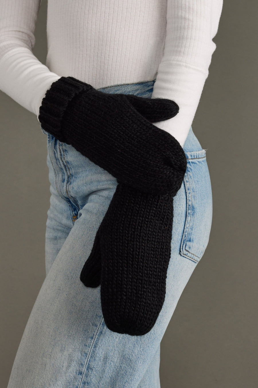 Person wearing black mittens with a plain background