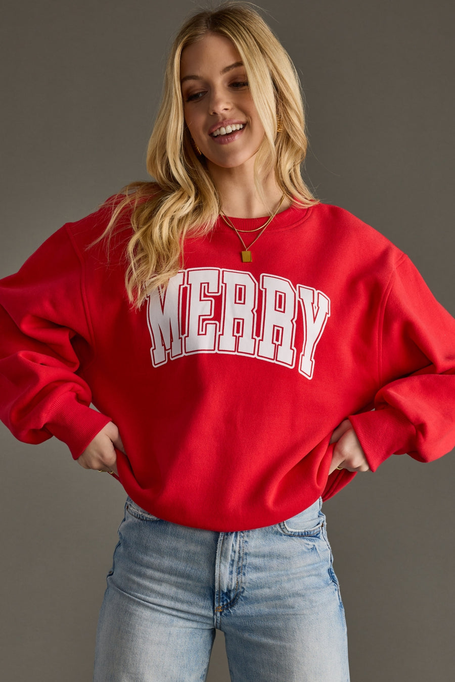 Person wearing a red sweatshirt with 'MERRY' text on a plain background