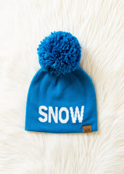 Blue beanie with pom-pom and 'SNOW' text on a white fluffy background